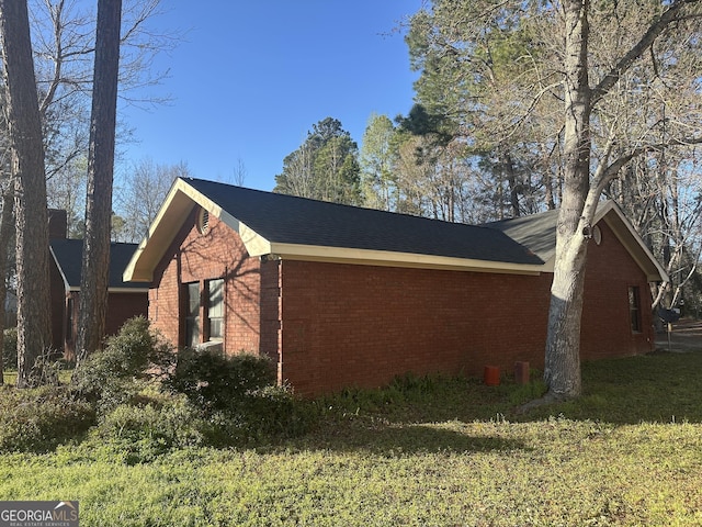 view of side of home featuring a yard, a chimney, and brick siding