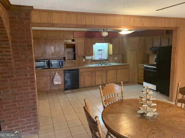 kitchen featuring a sink, light tile patterned floors, wooden walls, black appliances, and a toaster