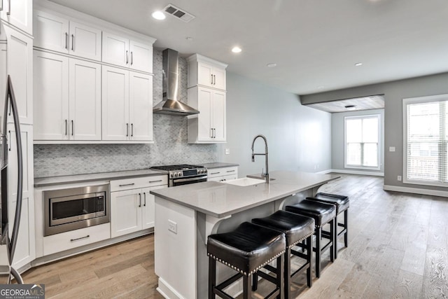 247 Franklin Rd, Atlanta, GA 30342 - kitchen with light wood finished floors, a sink, built in appliances, visible vents, and wall chimney range hood