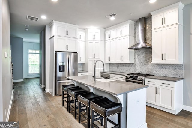 247 Franklin Rd, Atlanta, GA 30342 - kitchen featuring tasteful backsplash, hardwood / wood-style flooring, appliances with stainless steel finishes, wall chimney range hood, and visible vents