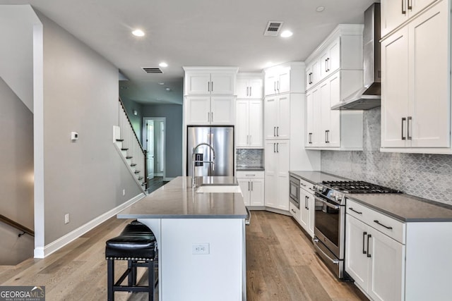 247 Franklin Rd, Atlanta, GA 30342 - kitchen featuring visible vents, appliances with stainless steel finishes, wall chimney range hood, and light wood-type flooring