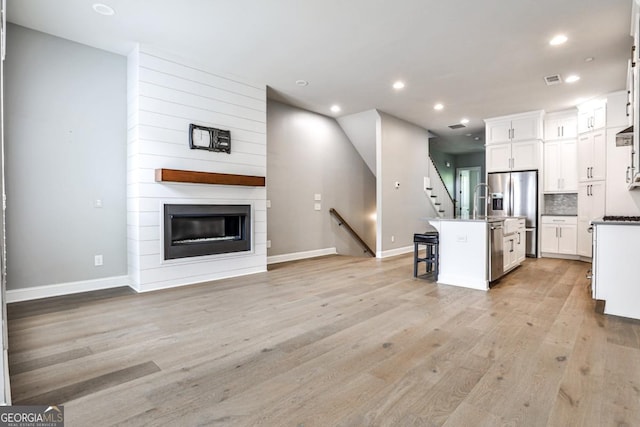 247 Franklin Rd, Atlanta, GA 30342 - kitchen featuring a kitchen island with sink, light wood-style flooring, a breakfast bar, appliances with stainless steel finishes, and open floor plan
