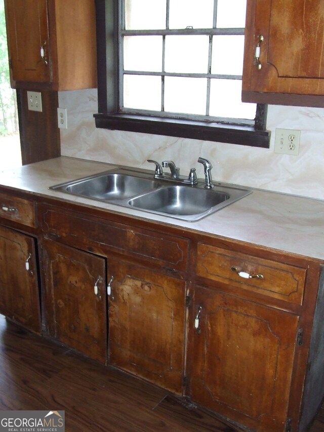 7225 Pineneedle Dr SW, Covington, GA 30014 - kitchen with a sink, light countertops, dark wood-type flooring, backsplash, and brown cabinets