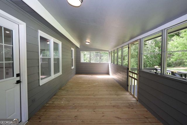 unfurnished sunroom featuring wood walls, vaulted ceiling, and hardwood / wood-style floors