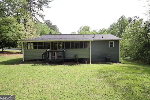 back of property with a sunroom, a yard, and central AC