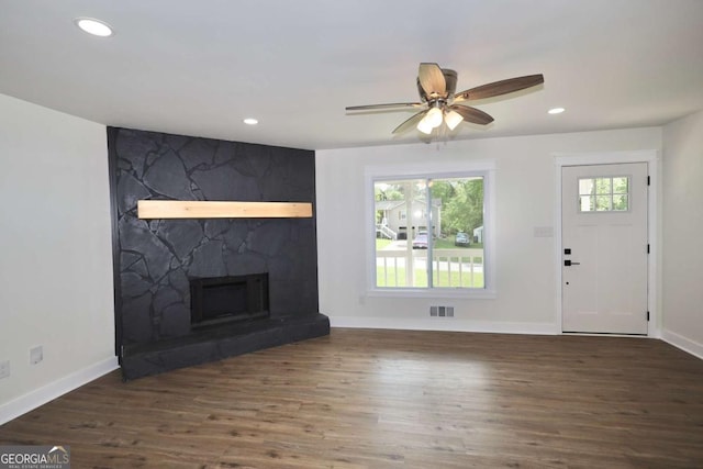 unfurnished living room with baseboards, a fireplace, wood finished floors, and visible vents