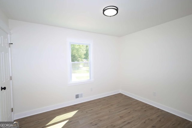 unfurnished room featuring baseboards, visible vents, and wood finished floors