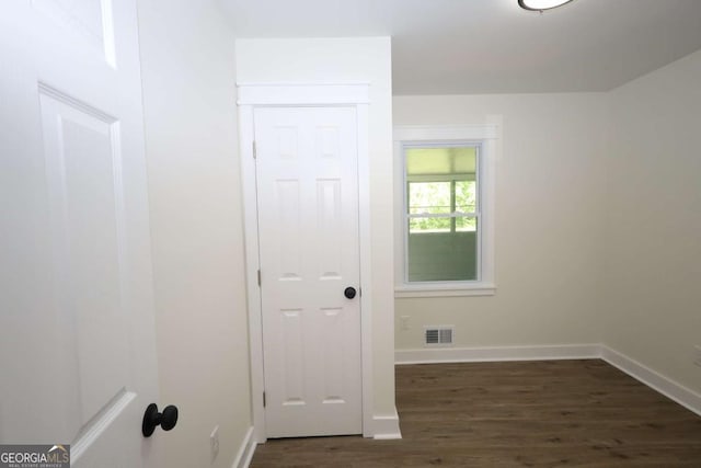 spare room featuring baseboards, dark wood-type flooring, and visible vents