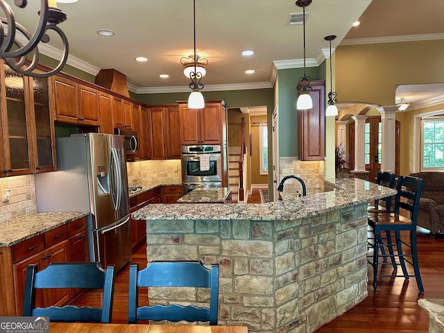 3397 Holly Glen Dr, Dacula, GA 30019 - kitchen featuring dark wood-style flooring, appliances with stainless steel finishes, a breakfast bar, ornate columns, and visible vents