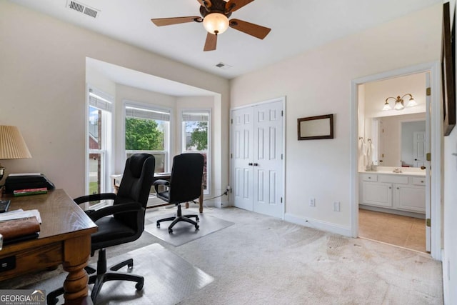 office space with visible vents, ceiling fan, and light carpet