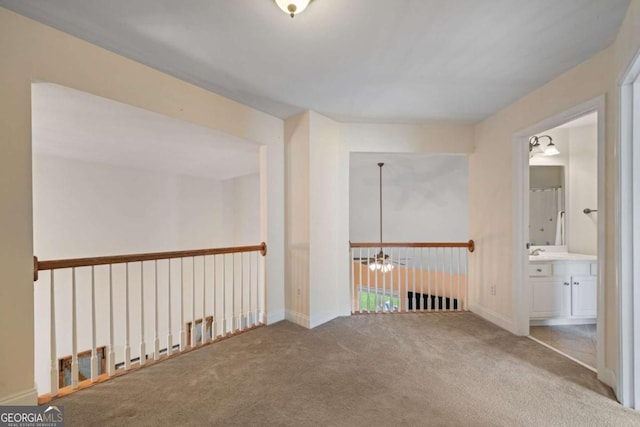 hall with an inviting chandelier, baseboards, carpet, and a sink