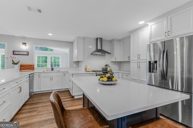 620 Clearbrook Ct, Marietta, GA 30068 - kitchen with appliances with stainless steel finishes, wall chimney range hood, light countertops, a kitchen breakfast bar, and recessed lighting