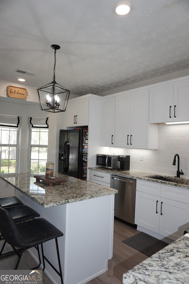 2566 Summit Cove Dr, Duluth, GA 30097 - kitchen with appliances with stainless steel finishes, a sink, dark wood-style floors, white cabinets, and a breakfast bar area