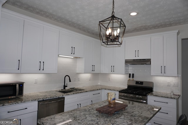 2566 Summit Cove Dr, Duluth, GA 30097 - kitchen with appliances with stainless steel finishes, under cabinet range hood, a sink, white cabinetry, and a chandelier