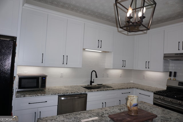 2566 Summit Cove Dr, Duluth, GA 30097 - kitchen with stainless steel appliances, a sink, under cabinet range hood, white cabinetry, and decorative backsplash