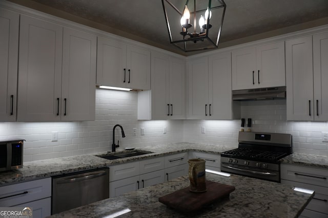 2566 Summit Cove Dr, Duluth, GA 30097 - kitchen featuring appliances with stainless steel finishes, a sink, under cabinet range hood, backsplash, and white cabinets