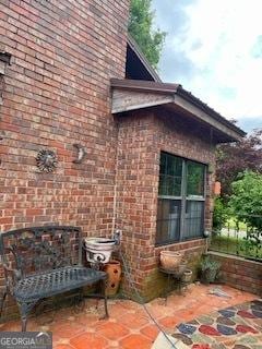view of property exterior featuring a patio and brick siding