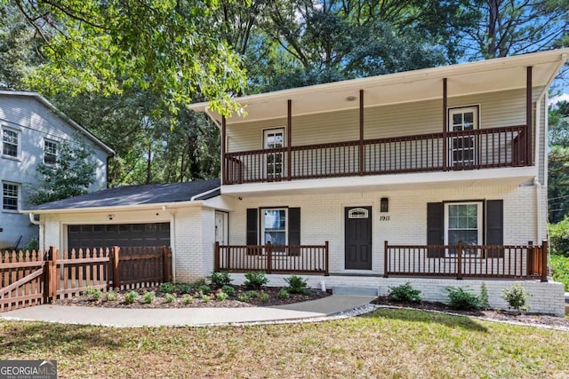 front facade with fence, covered porch, a garage, and a balcony