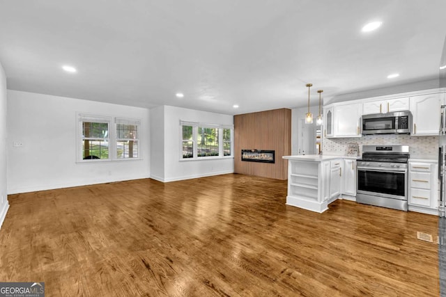 276 Greentree Pkwy, Macon, GA 31220 - kitchen featuring white cabinets, light countertops, stainless steel appliances, open floor plan, and wood finished floors