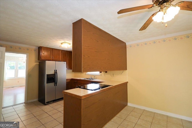 kitchen with brown cabinetry, a peninsula, stainless steel refrigerator with ice dispenser, cooktop, and light tile patterned floors