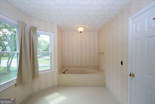 full bath featuring baseboards, a textured ceiling, wallpapered walls, and a bath