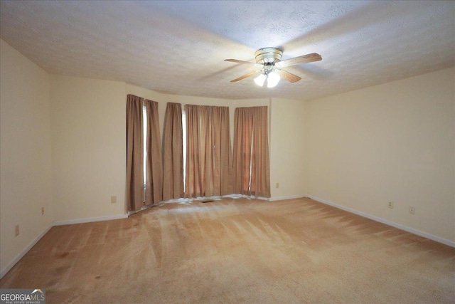 empty room with baseboards, light carpet, and a ceiling fan