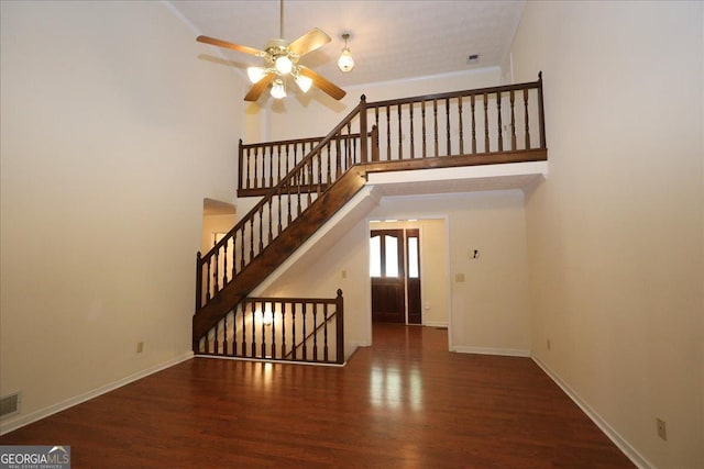 unfurnished living room featuring wood finished floors, baseboards, a high ceiling, stairway, and a ceiling fan