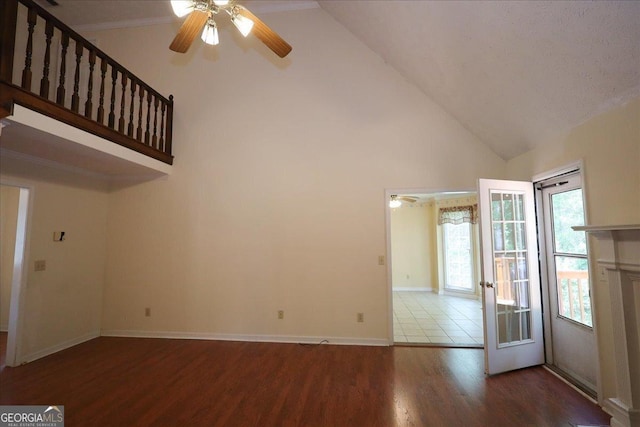 unfurnished living room with baseboards, ceiling fan, wood finished floors, and high vaulted ceiling