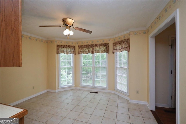 empty room featuring visible vents, crown molding, baseboards, ceiling fan, and light tile patterned floors