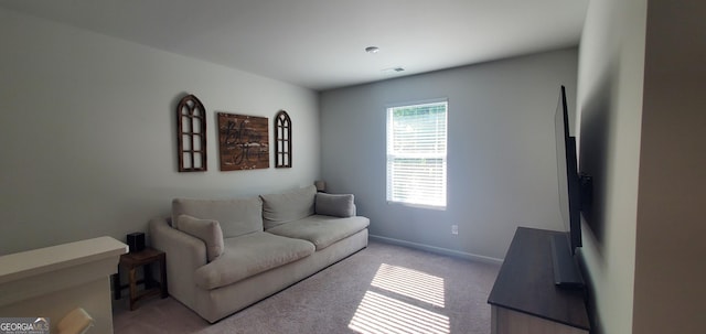 living area featuring baseboards, visible vents, and light carpet