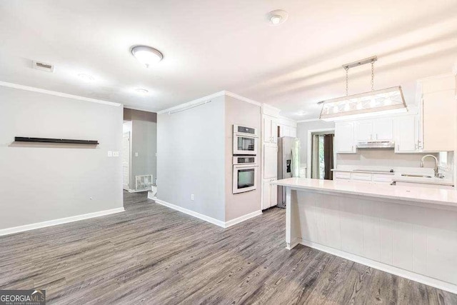kitchen featuring a sink, light countertops, white cabinets, dark wood-style floors, and ornamental molding