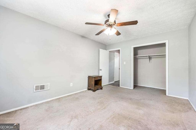unfurnished bedroom featuring a textured ceiling, visible vents, baseboards, and carpet