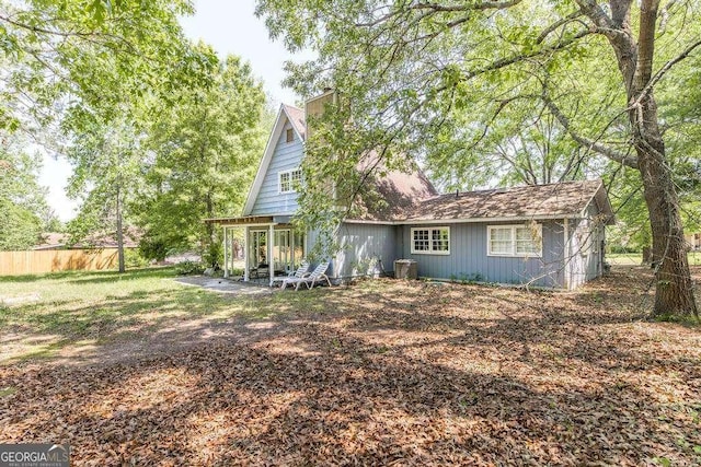 rear view of property with fence, a patio, and a chimney