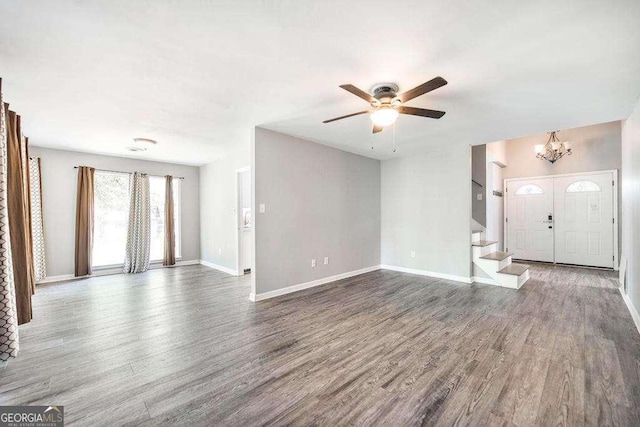 unfurnished living room with baseboards, ceiling fan with notable chandelier, stairs, and wood finished floors