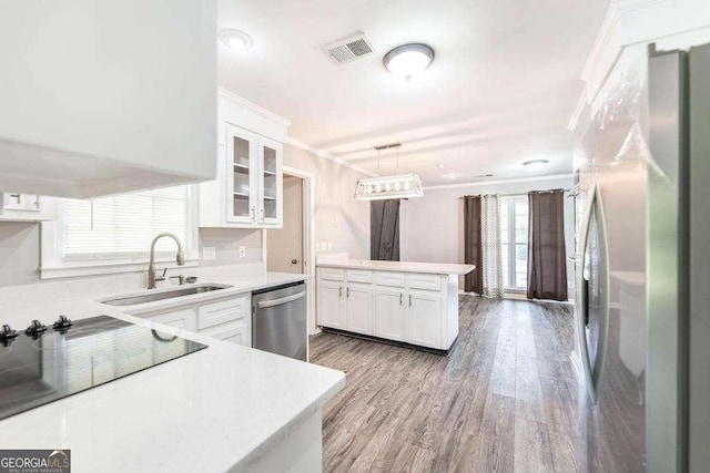 kitchen with a sink, appliances with stainless steel finishes, white cabinets, and ornamental molding