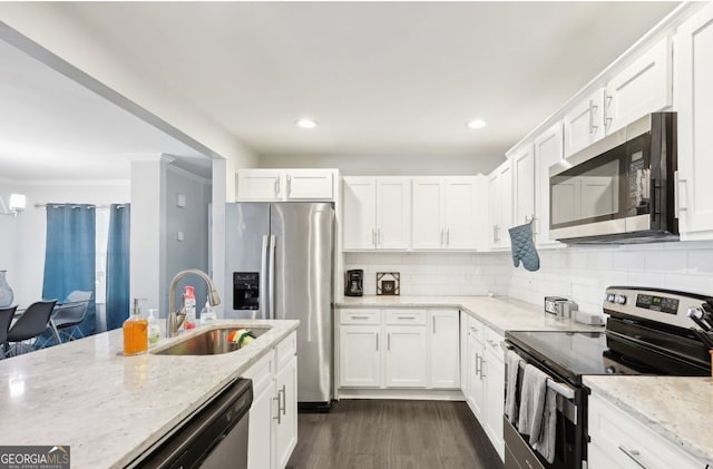 kitchen with white cabinetry, decorative backsplash, a sink, stainless steel appliances, and dark wood finished floors