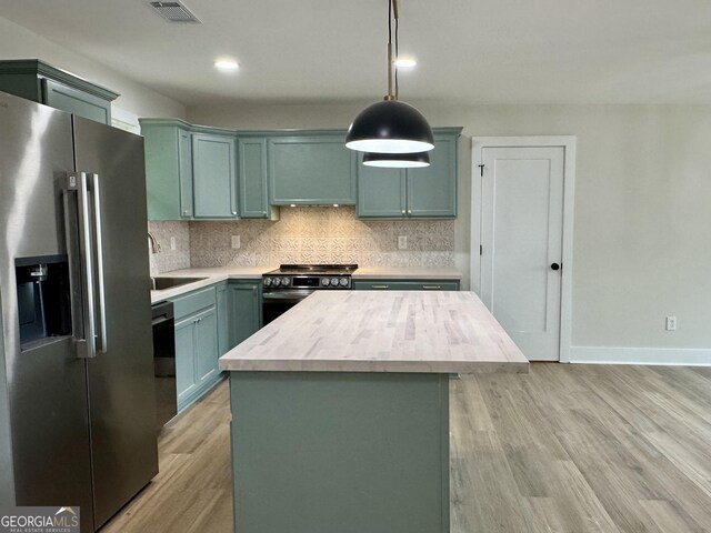 101 Newsome St, Union Point, GA 30669 - kitchen featuring appliances with stainless steel finishes, a sink, light countertops, light wood-style floors, and decorative backsplash