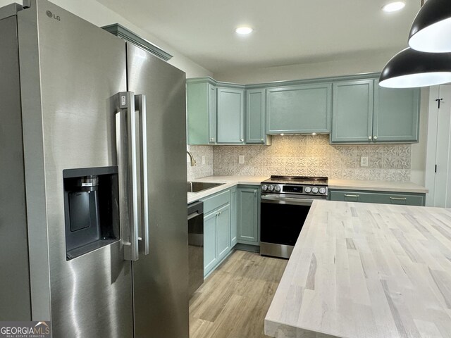 101 Newsome St, Union Point, GA 30669 - kitchen featuring stainless steel appliances, a sink, light wood-style flooring, decorative backsplash, and pendant lighting