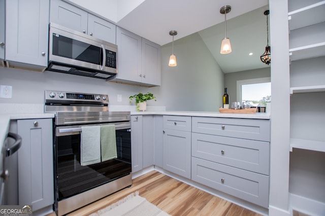 kitchen with appliances with stainless steel finishes, light wood-style floors, gray cabinetry, light countertops, and decorative light fixtures
