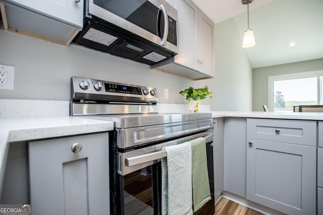 kitchen with gray cabinets, light stone countertops, appliances with stainless steel finishes, light wood-type flooring, and pendant lighting