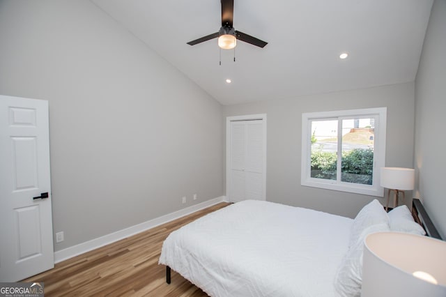 bedroom featuring recessed lighting, a closet, lofted ceiling, baseboards, and wood finished floors