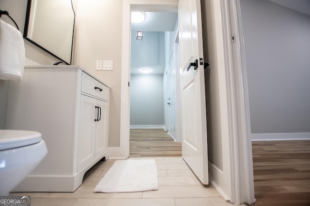 bathroom featuring baseboards, wood finished floors, and toilet