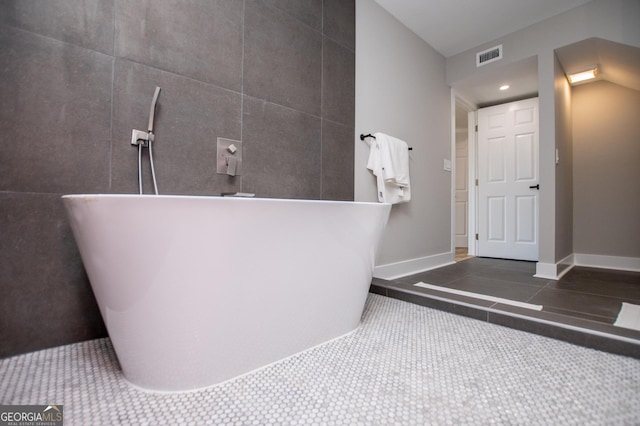 bathroom featuring visible vents, a freestanding bath, and baseboards