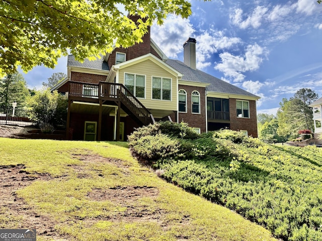 rear view of property featuring stairs, a wooden deck, a chimney, fence, and brick siding