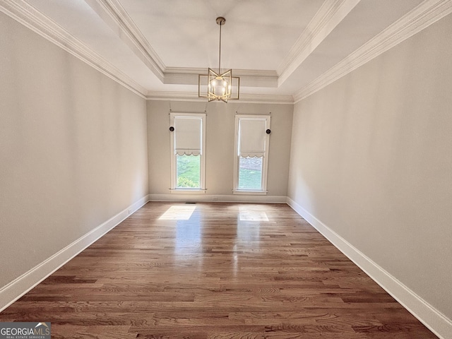 unfurnished dining area featuring wood finished floors, baseboards, a raised ceiling, a notable chandelier, and crown molding