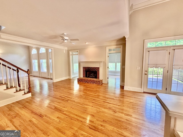 unfurnished living room with crown molding, stairs, and light wood-type flooring
