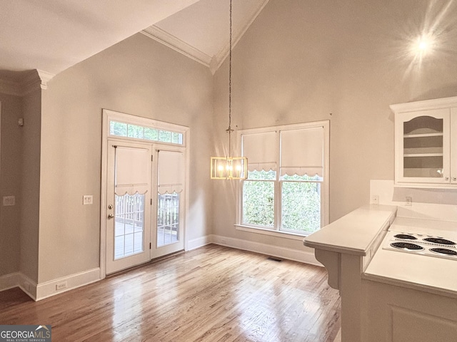 unfurnished dining area with wood finished floors, an inviting chandelier, crown molding, and plenty of natural light