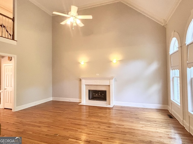 unfurnished living room with ornamental molding, high vaulted ceiling, wood finished floors, and a healthy amount of sunlight