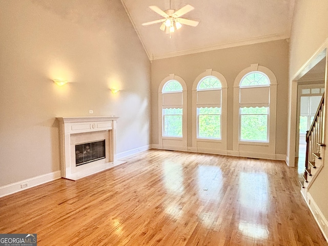 unfurnished living room with a premium fireplace, high vaulted ceiling, a ceiling fan, stairs, and ornamental molding
