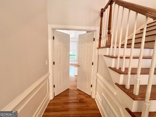 staircase with wainscoting, wood finished floors, and a decorative wall